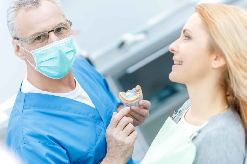 Dentist showing a dental model to a patient during a consultation.