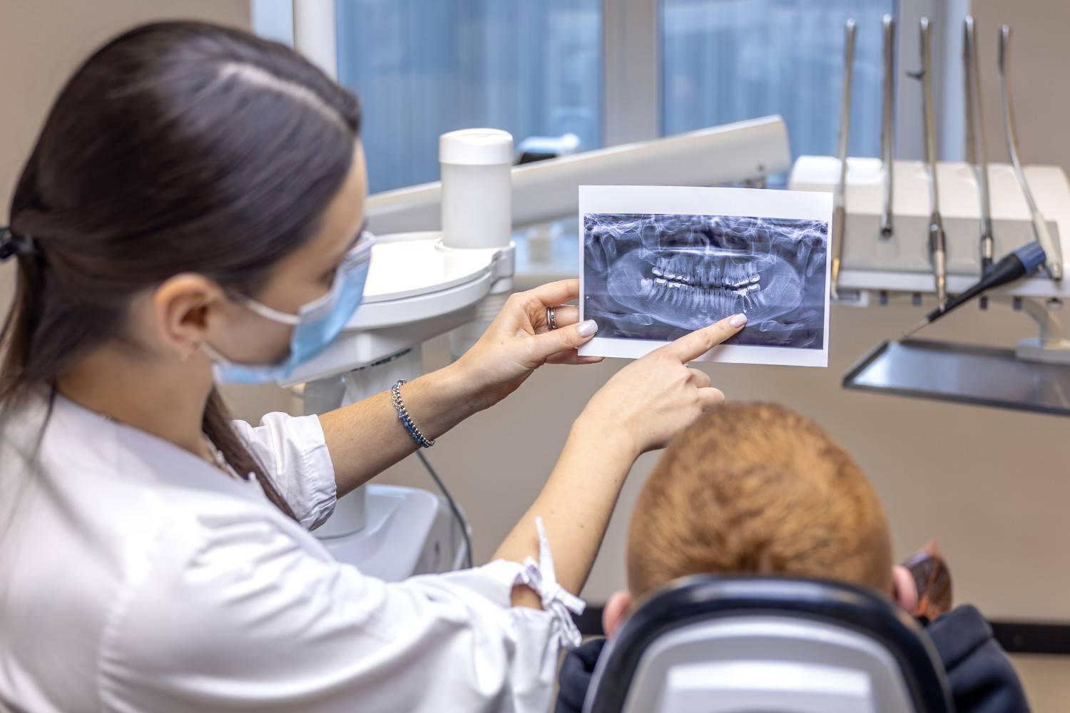 Dentist reviewing dental X-ray with patient in treatment room.
