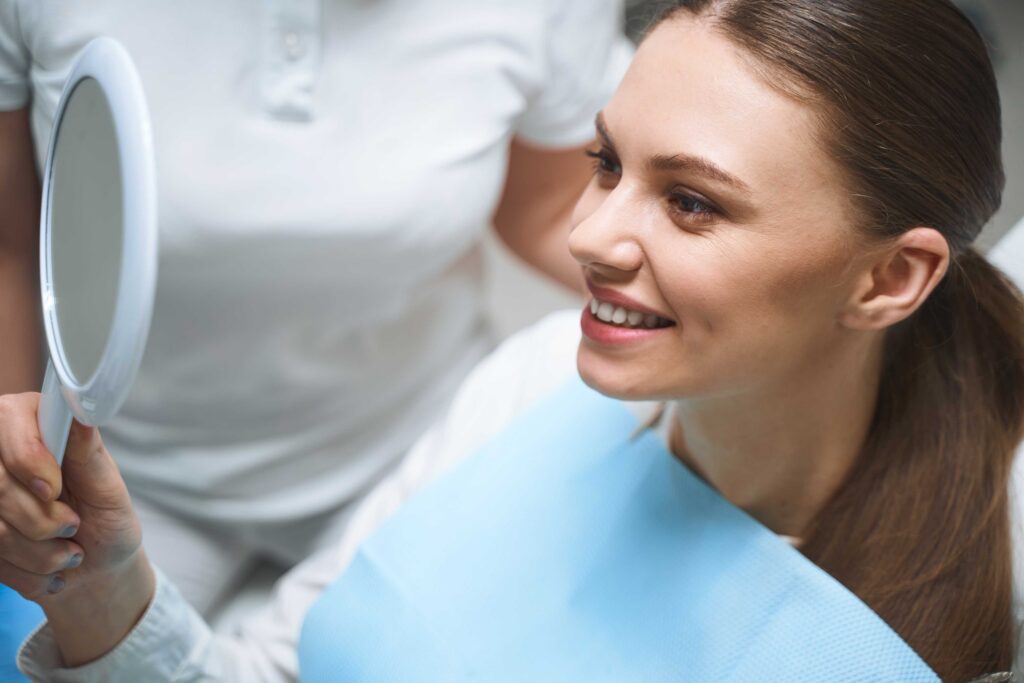 Smiling patient checking her smile in a mirror.